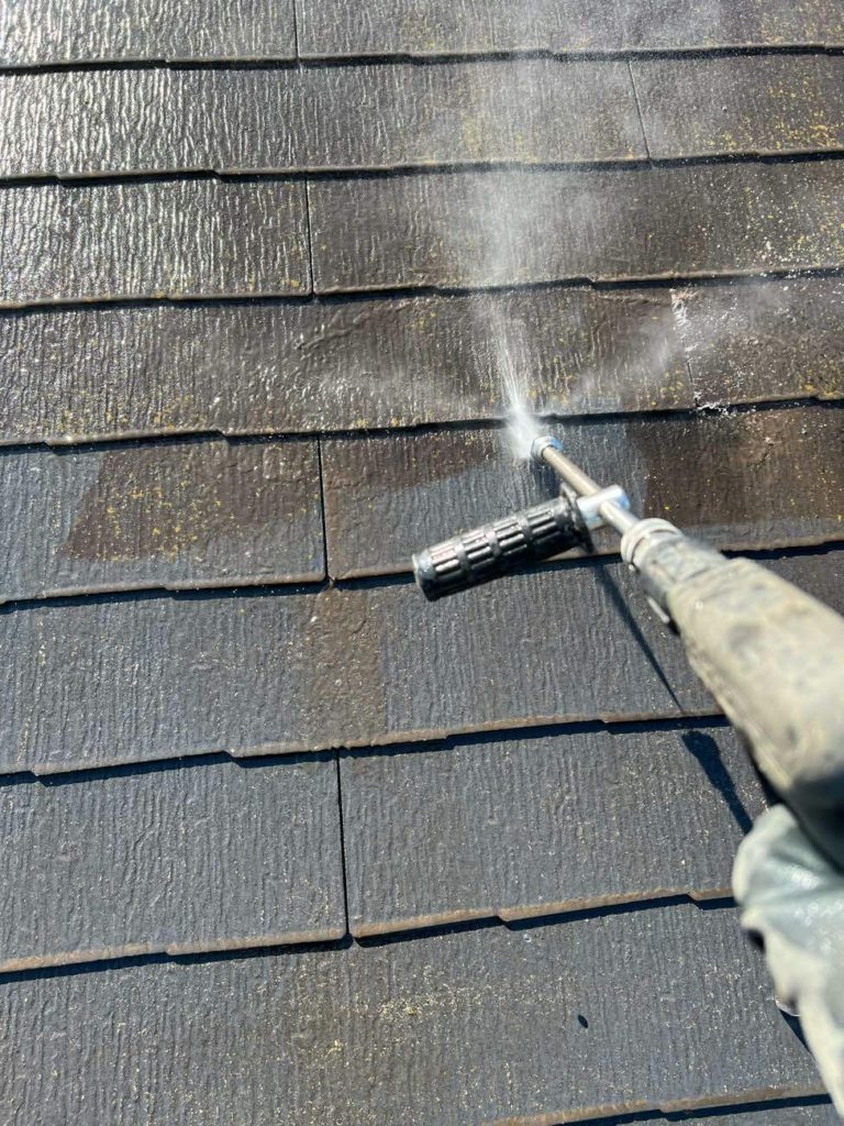 屋根の高圧洗浄を行う様子です。洗浄も足場設置と同様、雨天でも作業を行います。