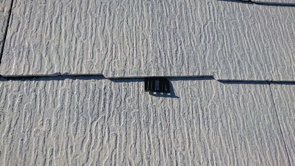 2回目の下塗り終了後にタスペーサーを挿入します。縁切りをせず、塗膜で屋根と屋根の隙間がふさがってしまうと、屋根勾配と隙間の関係で毛細管現象が起こり、雨水が排出されなうなってしまいます。これを防ぐために必要な作業です。