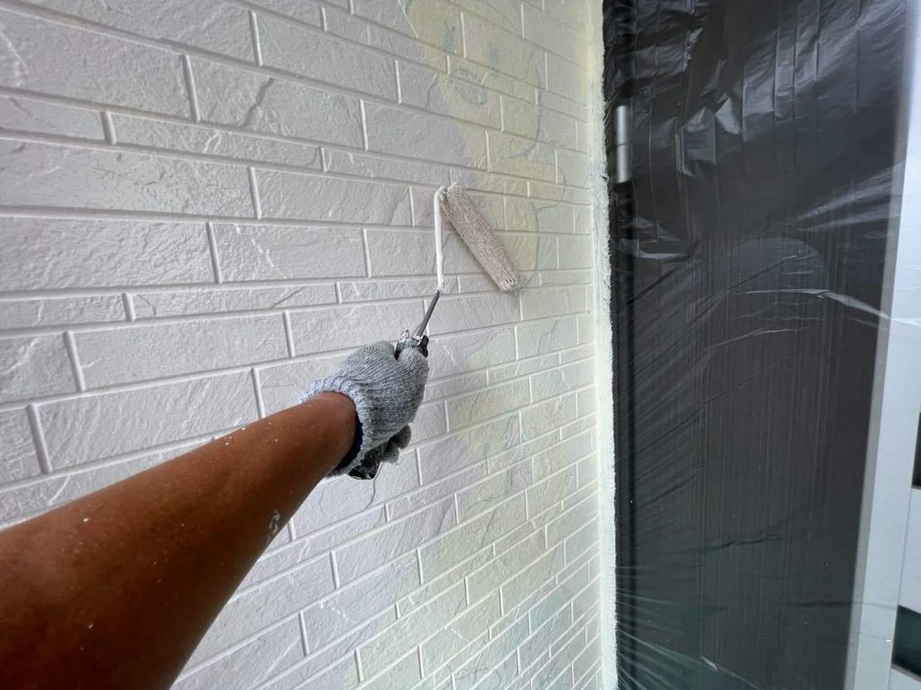 サイディング外壁に2回目の下塗りを行う様子です。ユウマペイントでは、下塗りを2回行う「4回塗り」を標準仕様としています。