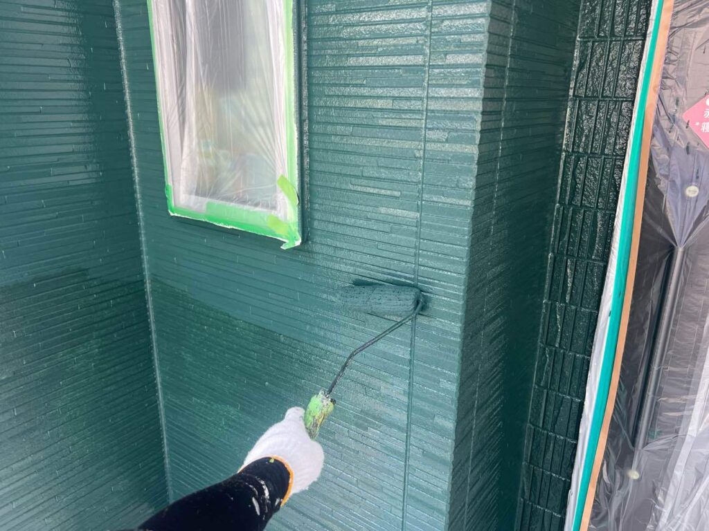 外壁の中塗りを行う様子です。中塗りの塗料は、お選びになった色番で塗装いたします。（写真色：SC-40 ダークグリーン）