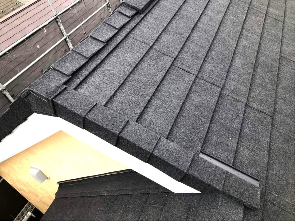 ディプロマットでカバー工事を行った後の屋根の写真です。カラーはオニキスというブラック系です。ディプロマットは日本建材センターでの風速実験（どのくらいの風速で屋根が飛ばされるのか）を検証した結果、令和元年東日本台風 （台風15号・19号）が関東地方に上陸した際の千葉市中央区で観測した最大瞬間風速55m/sを超える65m/sでも飛ばされなかったという結果を得ています。地域の皆様の安心で安全な暮らしを守るという意味では最も適した屋根材です。