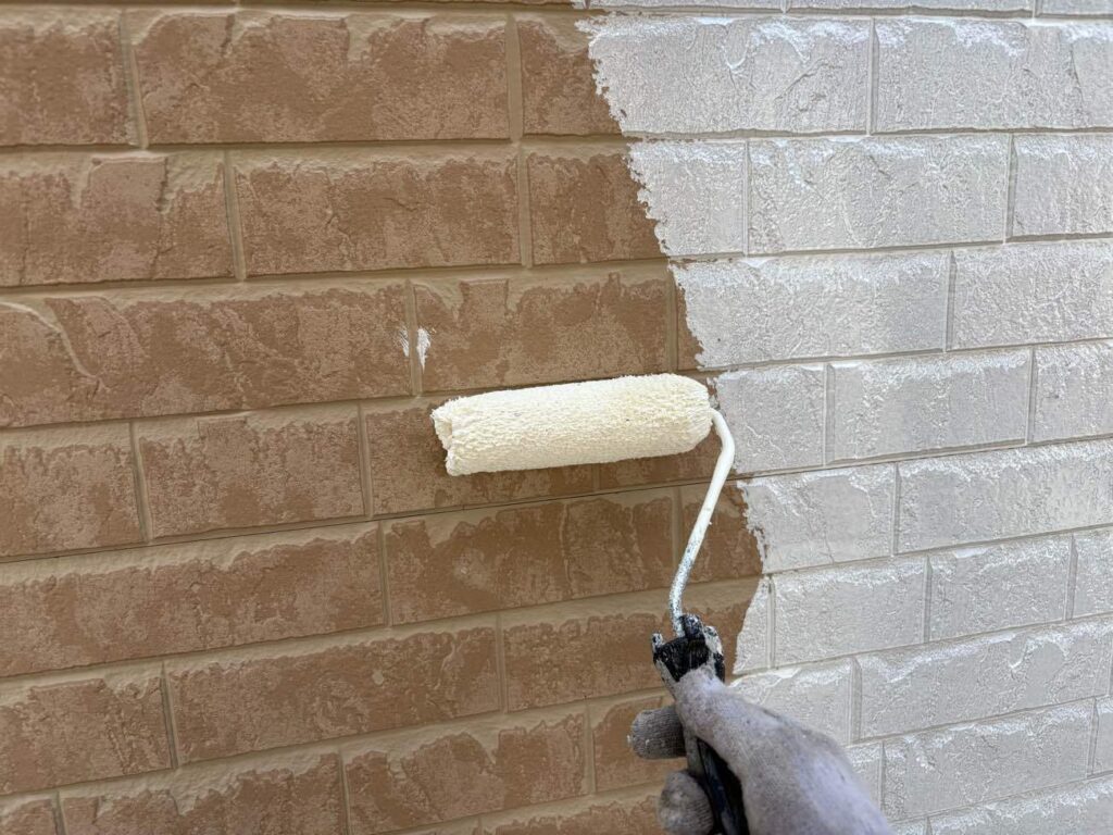 1回目の下塗りを行う様子です。ユウマペイントでは下塗りを2回行い、かつ下塗り材を変えて施工しています。1回目はファイン浸透シーラーです。このシーラーを塗る大きな目的の一つは「密着力を上げる」です。外壁は劣化するとチョーキング現象が出ているのですが、高圧洗浄をしてもどうしても取り切れないことがあります。それを抑えるためにシーラーで塗装を行い、2回目の下塗りへ移っていきます。