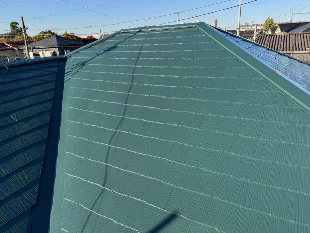 屋根塗装工事完了後の写真です。屋根は日本塗装名人社のフッ素UVコート溶剤Ⅱ遮熱でSC-40ダークグリーンというカラーです。オレンジ系の外壁の鮮やかさが引き立つ組み合わせです。