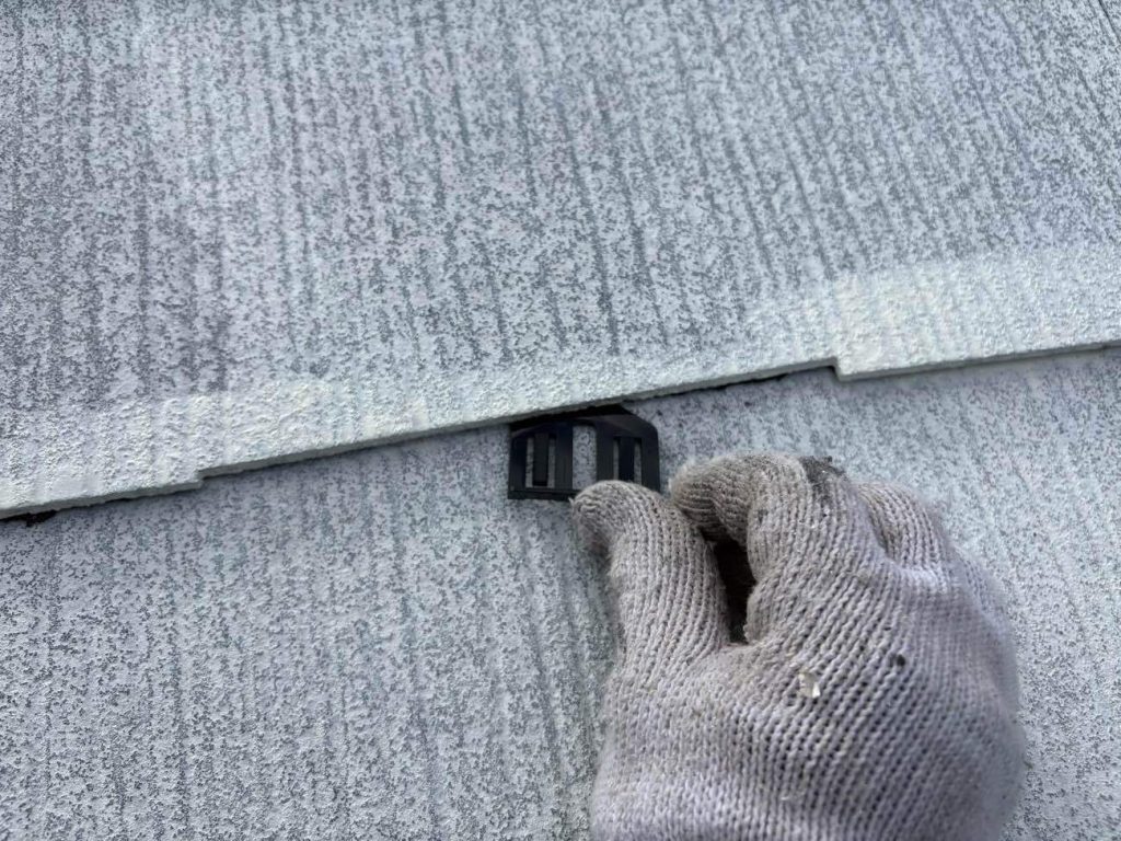 スレート屋根の塗装の際は、下塗り時タスペーサーを挿入します。塗膜によって屋根の隙間が埋まってしまうことを防ぐ役割があります。