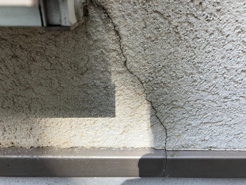 サッシまわりにひび割れ（クラック）が見られました。モルタル外壁によく現れるひび割れ（クラック）。経年劣化はもちろんですが、地震や交通振動、地盤の弱さなどで建物がわずかに動くと、 壁の一部に力が集中してひび割れが発生します。ひび割れには太さがあり、0.3mm未満は「ヘアークラック」といい、0.3mm以上は構造クラックと言います。