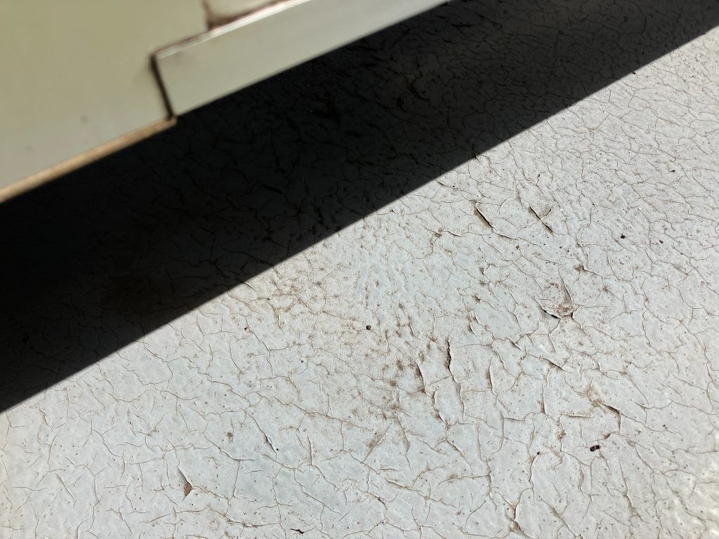 施工前のベランダ土間部分です。経年劣化や厚塗りによって硬化し、ひび割れ（通称：バキバキ）が目立つようになります。この状態を放置すると、見た目の劣化だけでなく、お客様が防水層自体の問題と誤解し、不安を感じる原因になります。ベランダは毎日、洗濯物を干したりで歩行します。歩行の摩擦やごみの堆積などによって汚れが目立つようになってしまいます。
