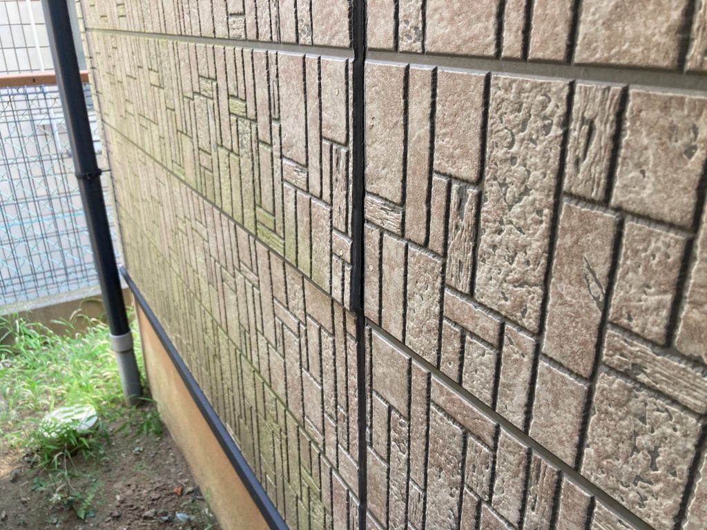 施工前の窯業系サイディングの写真です。日の当たらない面にコケの発生とサイディングの反りが見受けられます。