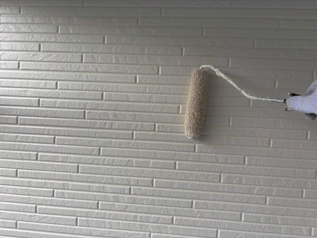 上塗りを行う様子です。ユウマペイントでは、中塗りと上塗りは同色（超低汚染リファイン1000MF-IR（8091ブロークンホワイト））です。見た目と品質に影響が出る大事な工程ですので、塗り漏れやムラが出ないよう丁寧に施工いたします。