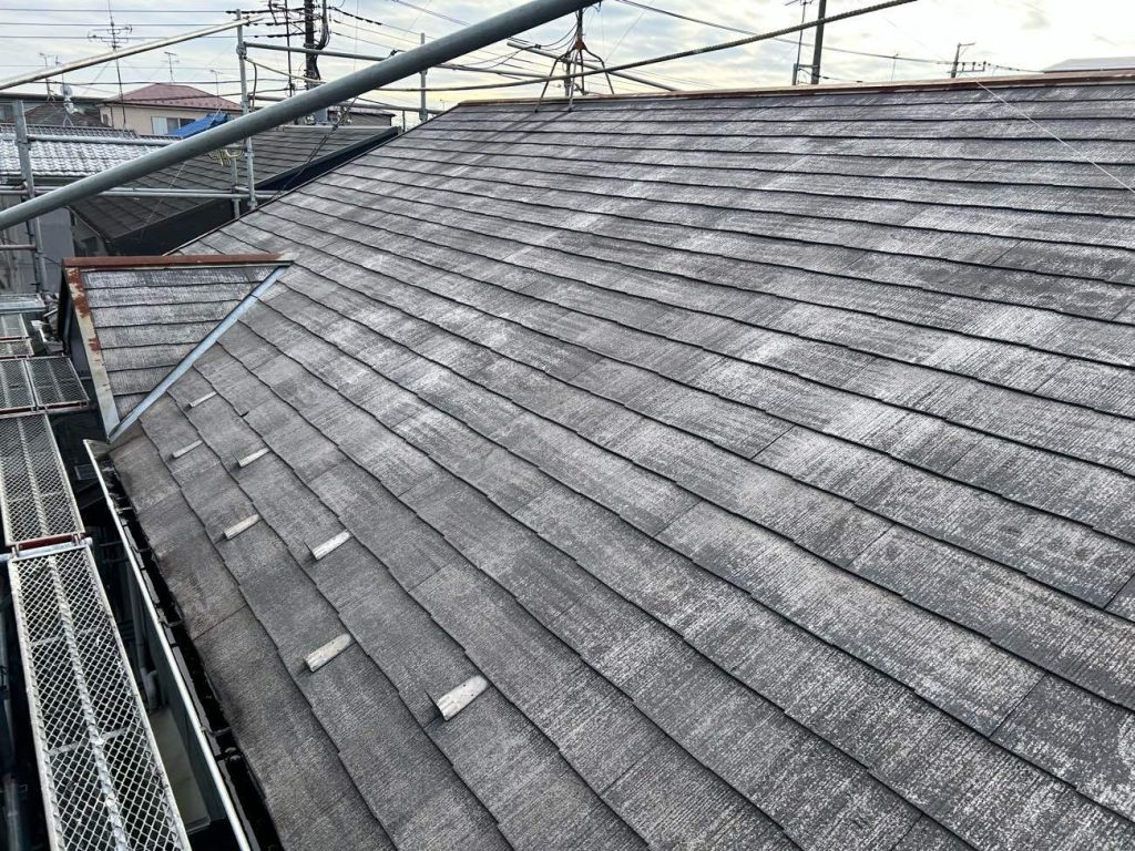 根（コロニアル）の高圧洗浄を終えた直後の写真です。築30年分の蓄積された土埃や古いコケ、剥がれかけた脆い塗膜を、業務用の高圧洗浄機で根こそぎ洗い流しました。白っぽく見えているのは、汚れが落ちて屋根材の本来の姿（素地）が露出しているためです。新しく塗る塗料を屋根にしっかりと密着させるためには、この「徹底的な洗浄」が欠かせません。洗浄後、塗装の工程（下塗り・中塗り・上塗り）に入っていきます