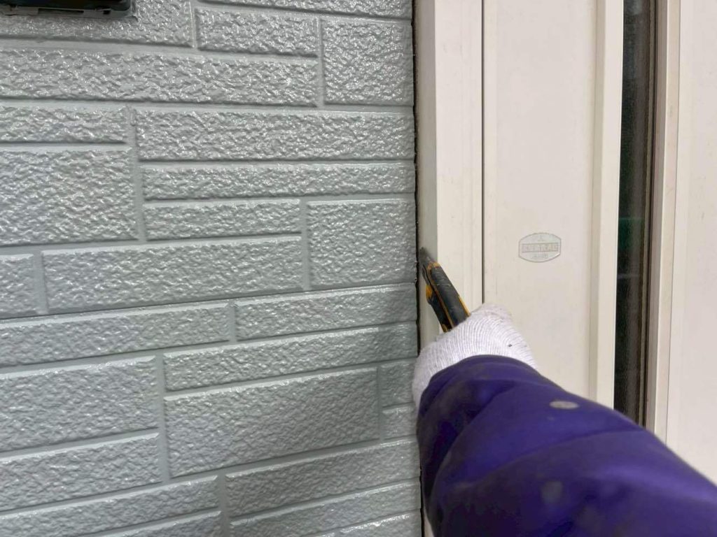 写真は玄関ドアまわりのシーリングを撤去している様子です。ユウマペイントでは、塗装後に新規シーリング材を打ち替える「後打ち工法」を採用しています。また、目地・サッシ関わらず撤去・打ち替えを標準施工としています。