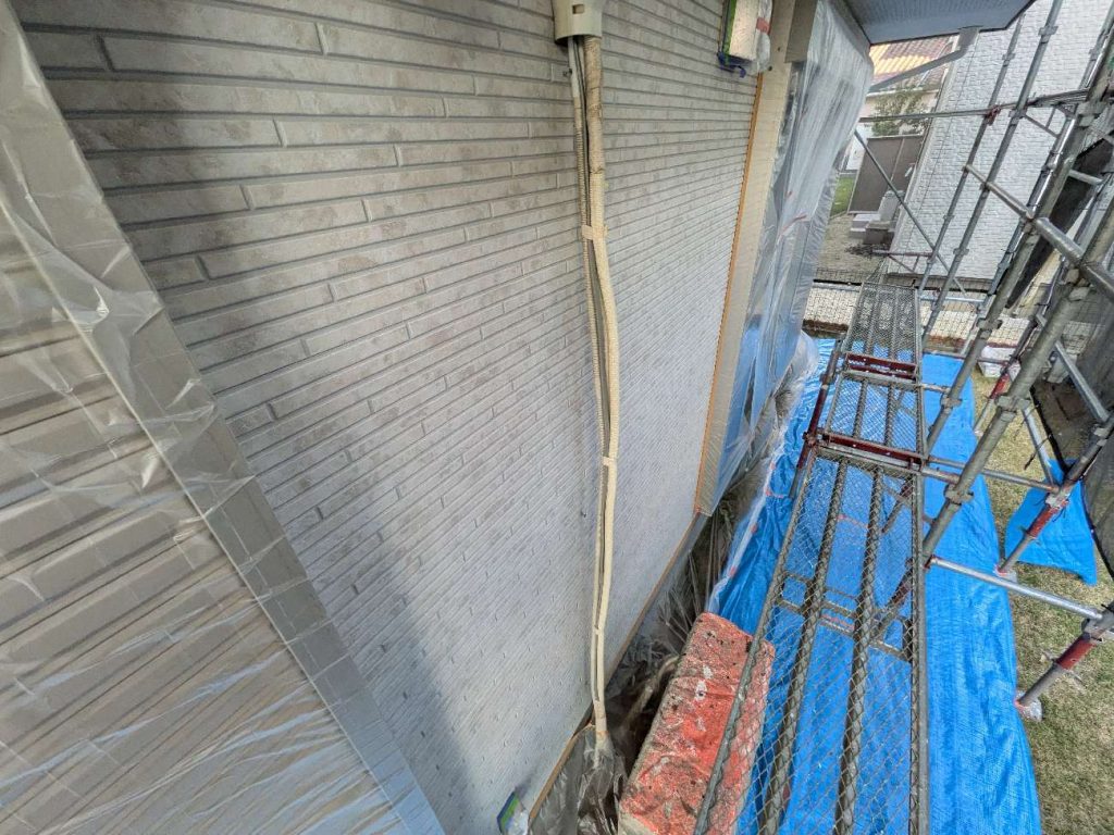 高圧洗浄後、塗装前に窓や土間（コンクリートや土部分）など塗料が付着しないための養生作業をします。また、エアコンカバーは塗装前に取り外し、エアコンカバー裏も塗装をしていきます。