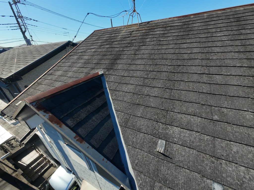 施工前のスレート屋根の写真です。スレート屋根の表面塗膜が劣化し水を吸いやすい状態になっています。また、棟板金の表面が錆びています。