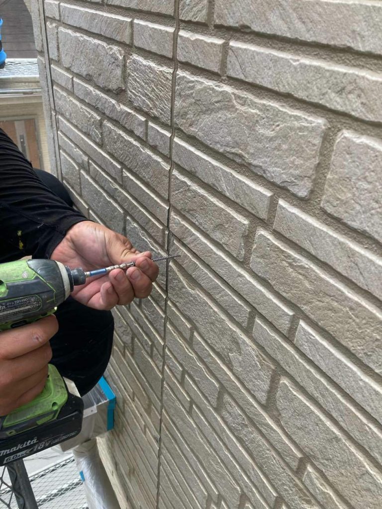 サイディング外壁の浮きや反りを補修する「ビス止め（増し打ち）」作業の様子です。経年劣化で浮いてしまった外壁材を、ビスでしっかりと下地に固定し直します。雨水の浸入を防ぎ、その後の塗装やシーリングを長持ちさせるために欠かせない大切な下地処理工程です。