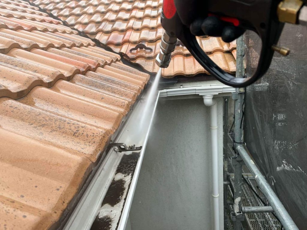 塗装工事の起点となる高圧洗浄工程です。業務用高圧洗浄機を使用し、外壁や屋根に付着した長年の汚れ、カビ、苔などを丁寧に洗い流します。今回は塗装を行わない洋瓦屋根も念入りに洗浄し、本来の美しさを取り戻しました。外壁は古い塗膜の粉を落とし、新しく塗る塗料の密着性を高めるための重要な下準備となります。