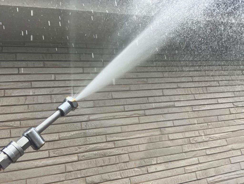 塗装工事の起点となる高圧洗浄工程です。業務用高圧洗浄機を使用し、外壁や屋根に付着した長年の汚れ、カビ、劣化した旧塗膜の粉を洗い流します。特に洋瓦の重なり部分やサイディングの目地など、汚れが溜まりやすい箇所は時間をかけて念入りに洗浄します。新しく塗る塗料の密着性を最大限に高めるための重要な下準備です。