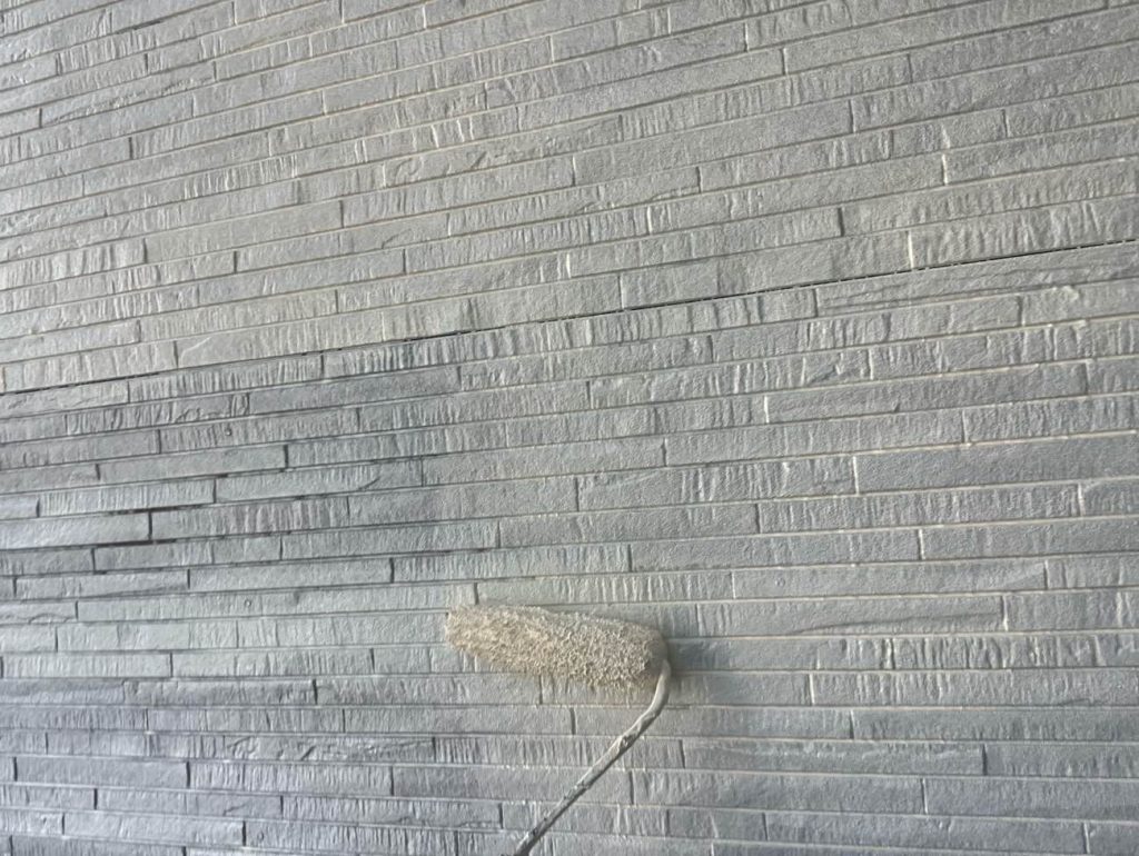 外壁の下塗り2回目の工程です。日本ペイント水性シリコンエポサーフを塗布します。1回目のシーラーで固めた下地の上に微弾性を持つこの下地材を重ねることで、表面の微細なひび割れを埋めて平滑に整えます。下塗りを2回行うことで塗料の吸い込みを完全に止め、上塗り塗料の性能と美しい仕上がりを最大限に引き出します。