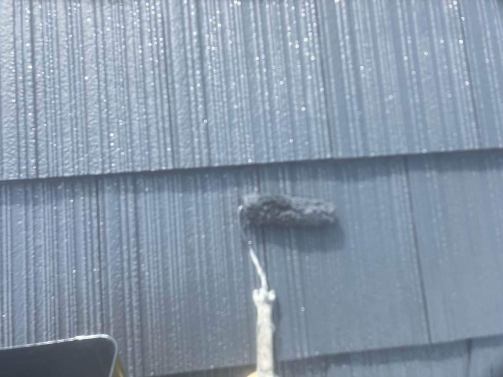 屋根の仕上げ工程です。日本塗装名人社無機UVコートルーフ遮熱を使用し、中塗りと上塗りの2回に分けて仕上げます。色は引き締まったチャコールグレー（SC-48）を採用。無機塗料の高い耐候性に加え、太陽光を反射する遮熱機能により屋根の表面温度上昇を抑え、過酷な環境からお住まいを強靭に守ります。