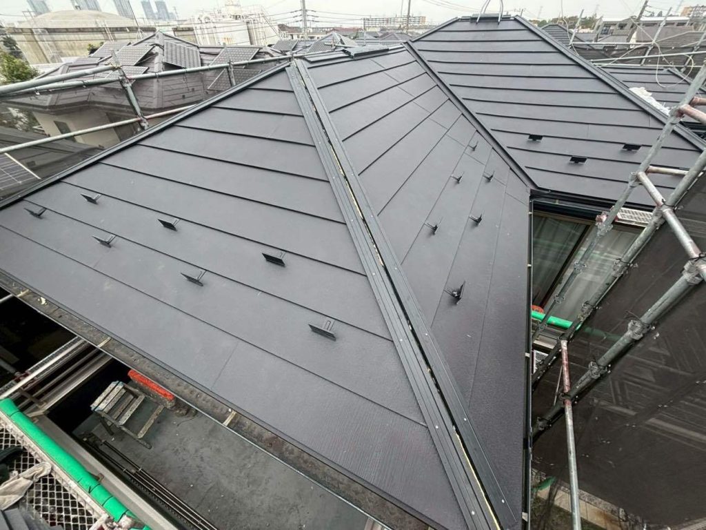 仕上げに、屋根の頂上部に新しい棟板金を設置します。ユウマペイントでは、板金を固定する下地（貫板）に、腐らない樹脂製の「タフモック」を採用しています。一般的な木製の貫板は経年による腐食が避けられませんが、樹脂製を用いることで水分による劣化や釘の浮きを永久的に防ぐことができます。この高耐久な下地に棟板金を被せ、側面からステンレスビスで確実に固定することで、台風などの強風でも飛散することのない、メンテナンスフリーな棟へと仕上げます。