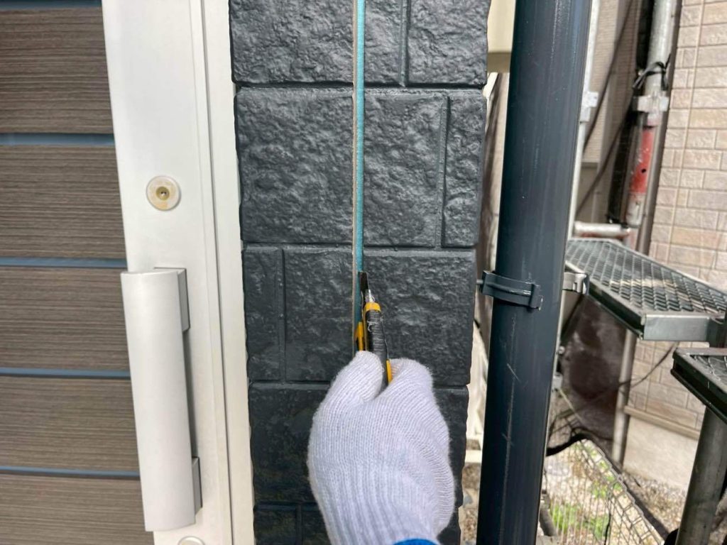 外壁の目地を埋めている古いシーリング材の撤去工程です。ユウマペイントでは、古い材の上から新しいものを被せるだけの簡易的な「増し打ち」ではなく、古いものを根元からすべて剥がす「撤去・打ち替え」を標準仕様としています。経年劣化で硬化し、ひび割れや隙間が生じたシーリング材をカッターで丁寧に取り除き、サイディングの断面を完全に露出させます。この徹底した撤去作業が、新しいシーリング材の密着性を高める重要な工程になります。