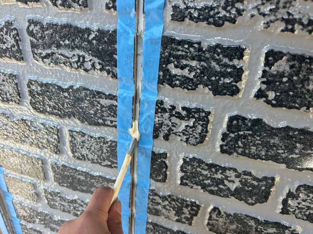 古いシーリング材を綺麗に撤去した後、目地の側面に専用の接着剤である「プライマー」を塗布する工程です。一見地味な作業ですが、これを怠ると新しく打ったシーリング材がすぐに剥がれたり、隙間が空いたりして雨漏りの原因になります。プライマーをハケで奥までムラなく塗布することで、サイディング材と新しいシーリング材を強力に密着させます。塗装における下塗りと同じように、防水機能を長期間維持するために決して欠かせない下準備です。