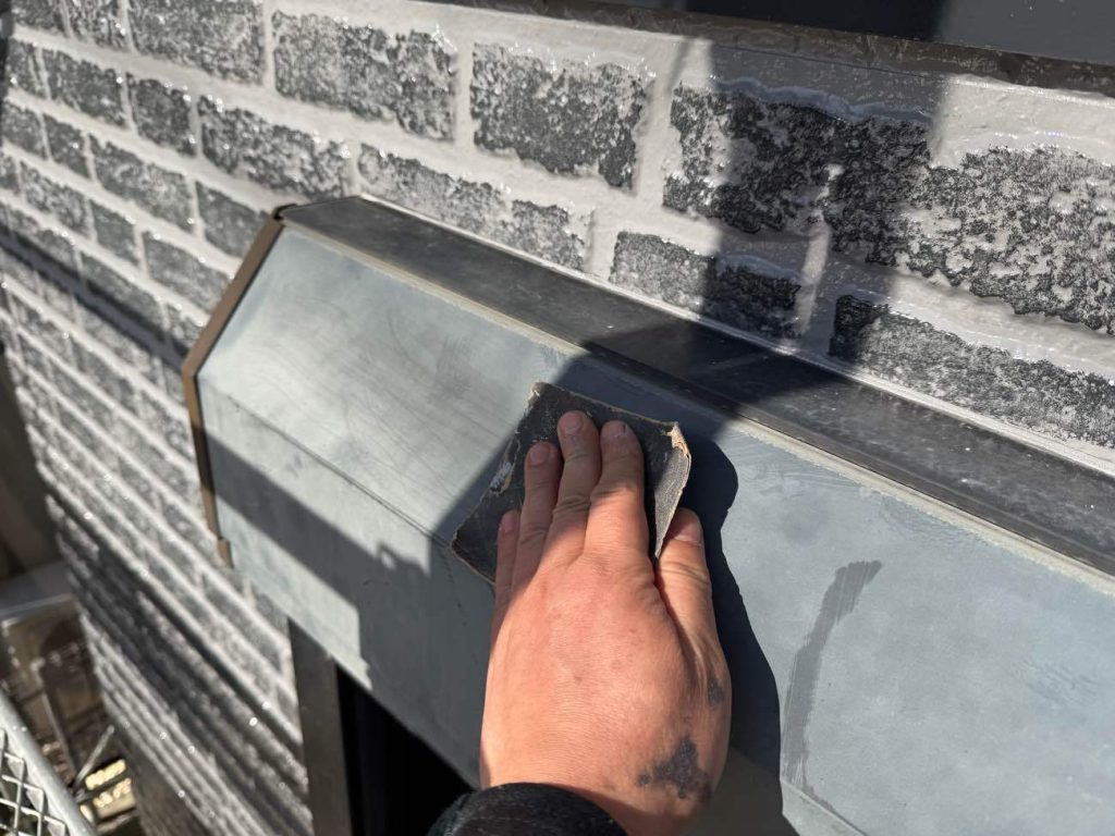 金属製であるシャッターボックスの塗装前下地処理です。金属を長持ちさせるためには、最初の「ケレン」で表面に発生した微細なサビをゴシゴシと確実に削り落とすことが何より重要になります。同時に表面に微小な凹凸をつけることで、塗料の密着力を飛躍的に高めます。その後、高圧洗浄では落としきれない金属表面の油分や不純物をシンナーで完全に脱脂（だっし）し、サビの早期再発や塗膜の浮きを未然に防ぐための完璧な下地を作り上げます。