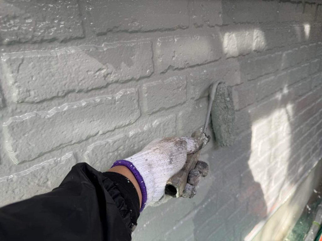 下塗りで整えた土台の上に、メインの仕上げ塗料「日本塗装名人社 無機UVコート水性」を塗布する工程です。塗装は「中塗り」と「上塗り」の2回に分けて丁寧に行います。まず中塗りで塗膜の適正な厚みを確保して耐久性の基盤を作り、乾燥後に上塗りを重ねて色ムラのない美しい艶と強靭な塗膜を完成させます。この塗料は紫外線に強い無機成分を配合した、約15年の耐久性を誇る超高耐候ハイブリッド塗料です。長期間にわたって色あせや汚れの付着を防ぎ、お住まいの美観を長く保ち続けます。