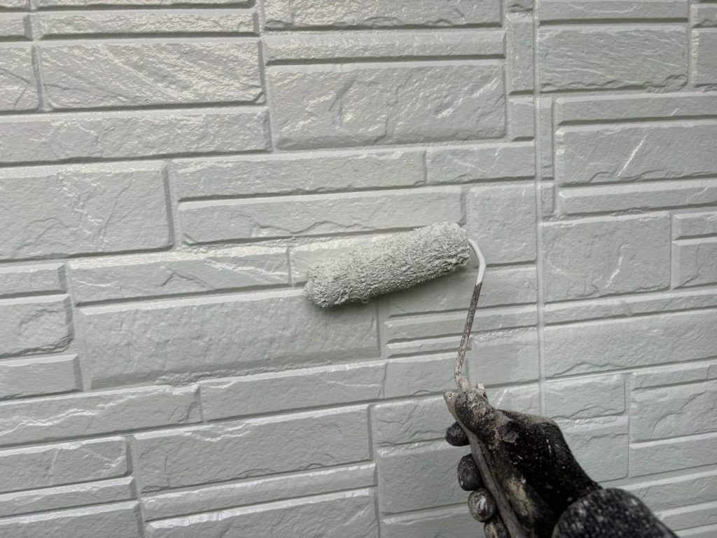 下塗りが乾燥した後、アステックペイントの「超低汚染リファイン1000MF-IR」で中塗りを行います。光沢を抑えた「3分艶」仕様で、部位に合わせて「アイアンバーグ」「ウィザードコッパー」「オフホワイト」の3色で塗り分けます。基準塗布量を守りながら均一な膜厚になるよう塗り広げ、防汚性や遮熱性を発揮させるベースを作ります。