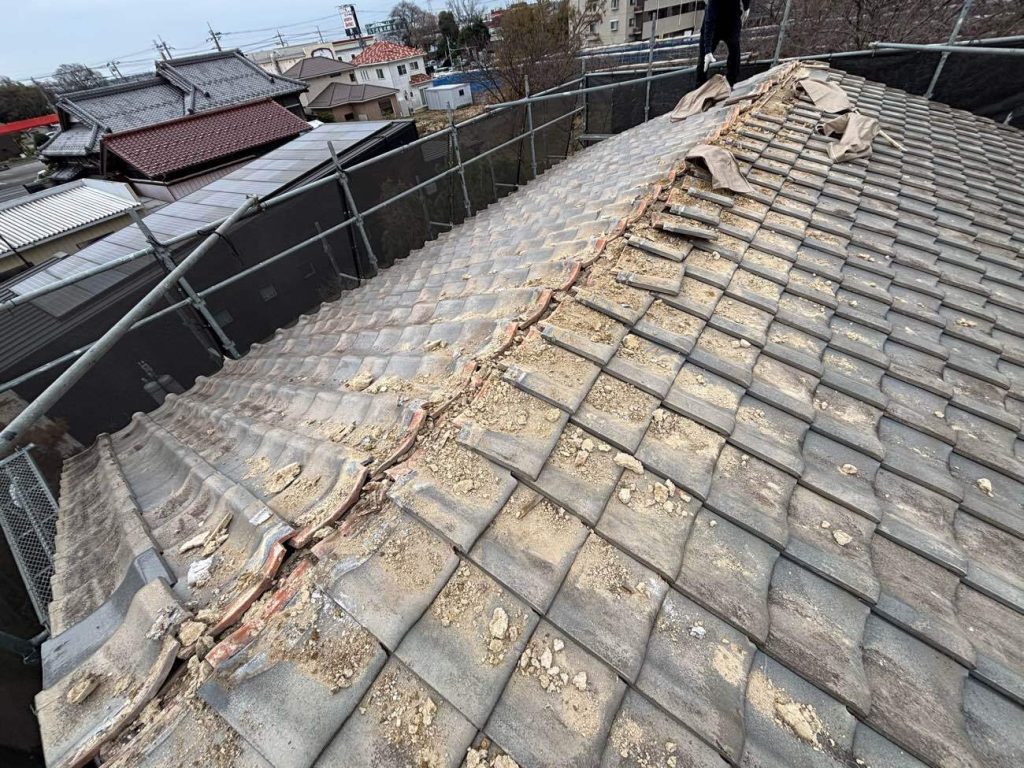 足場架設後、既存の陶器瓦の撤去を行います。写真は旨瓦を取り外している様子です。