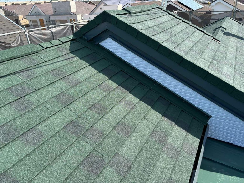 施工後の屋根写真です。既存のスレート屋根の上に、軽量な金属屋根「ディプロマット（エバーグリーン）」を用いたカバー工法を実施しました。 棟板金などの役物も確実に施工し、長期的な防水性を確保しています。