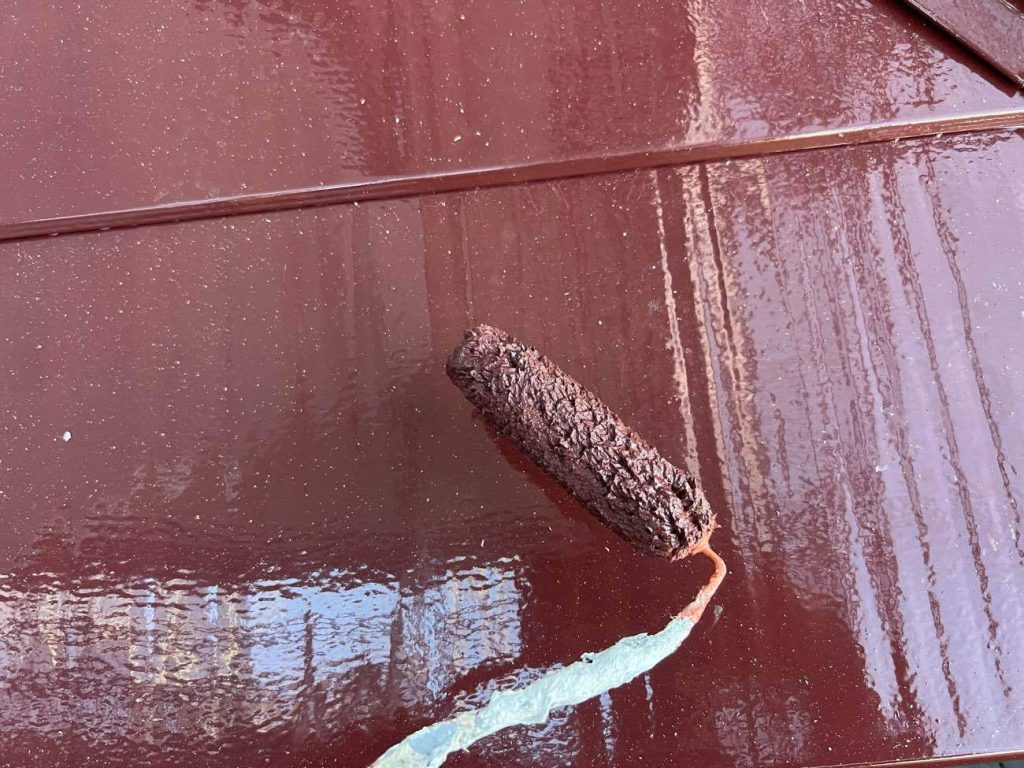 ガルバリウム鋼板の下屋根の塗装を行います。ガルバリウム鋼板は表面が平滑で塗料が密着しにくいため、入念なケレン作業（目荒らし）を行った後、「ガルバリウム鋼板にしっかりと密着する専用の下塗り材（プライマー）」を塗布します。これにより強固な接着面を形成し、上塗り材の早期剥離を防ぎながら仕上げます。