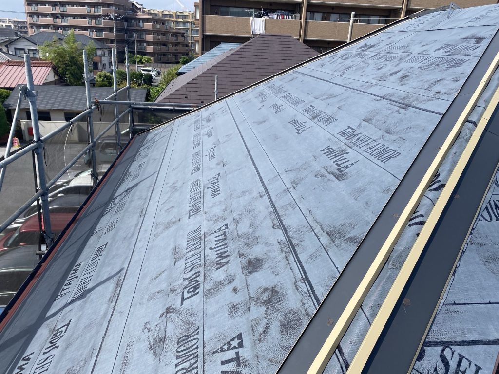 高圧洗浄後の既存屋根の上に、改質粘着防水シート「タディスセルフアーマー」を隙間なく敷き詰めた状態です。 自己粘着性を持ち屋根材に密着するため、釘穴からの雨水浸入も防ぐ高い防水性能を発揮します。 新しい屋根材の下で建物内部への漏水を防ぐ、重要な二次防水層となります。